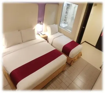 a hotel room with two beds and a window at Ritz Suites in Lumut