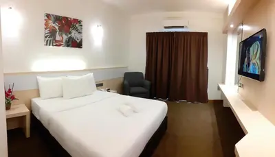 a hotel room with a white bed and a chair at SERDANG LAKE VIEW RESORT in Sungai Kechil