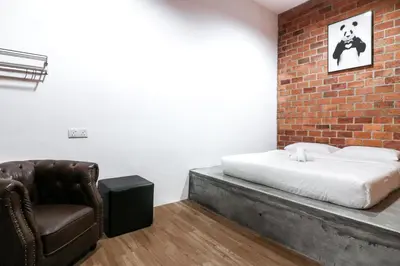 a bedroom with a brick wall and a bed and a chair at UrbanStay Industrial in Ipoh