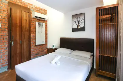 a bedroom with a white bed with a brick wall at UrbanStay Industrial in Ipoh