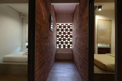 a hallway with two beds and a brick wall at UrbanStay Industrial in Ipoh