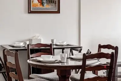 a dining room table with chairs and a table with plates and bowls at Tropicana 218 Macalister by Simply Penang in George Town