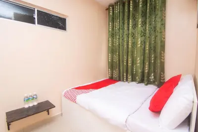 a small bedroom with a white bed with red pillows at Hotel O Hajah Rohayah in Tanjung Malim