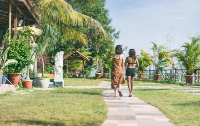 two women walking down a path in a park at Lost Paradise Resort in Batu Ferringhi
