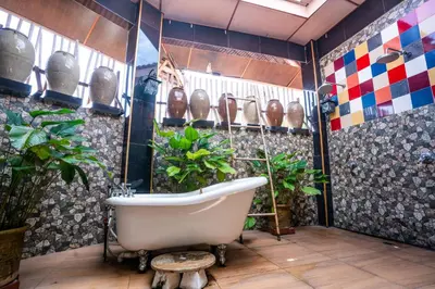 a bath tub in a room with plants and vases at Lost Paradise Resort in Batu Ferringhi