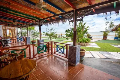a patio with tables and chairs and a view of the ocean at Lost Paradise Resort in Batu Ferringhi