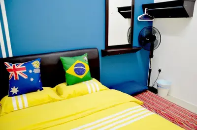 a bedroom with a bed with yellow sheets and a blue wall at The Woodz Homestay - 2 Storey Landed House in Cameron Highlands