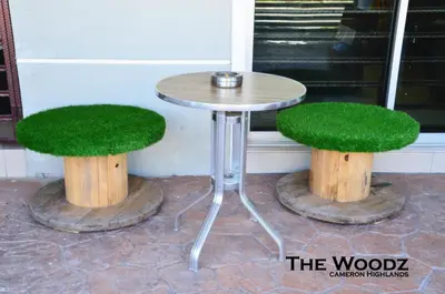 a table and two stump stools with grass on them at The Woodz Homestay - 2 Storey Landed House in Cameron Highlands