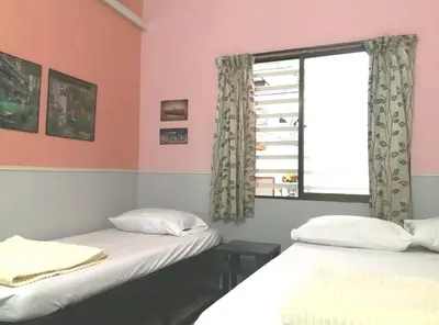 two beds in a room with a window at Hua Tang Homestay in Ipoh