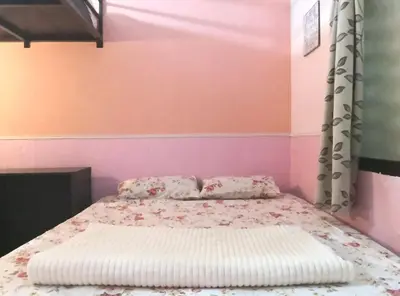 a bed in a bedroom with pink and pink walls at Hua Tang Homestay in Ipoh