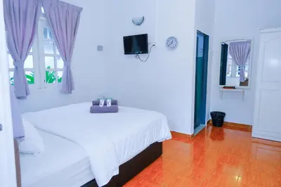 a white bedroom with a bed and a television at Vagary Pangkor in Pangkor