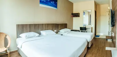 two beds in a hotel room with white sheets at K West Hotel in Sitiawan