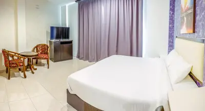 a bedroom with a bed and a table and a tv at K West Hotel in Sitiawan
