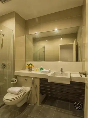 a bathroom with a toilet and a sink and a mirror at Luxfort 118 Service Suites in George Town