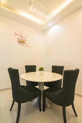 a white table with chairs and a white wall at Landed Cozy House Near SPICE, Airport in Kampong Manggis