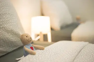 a small teddy bear sitting on the edge of a bed at Landed Cozy House Near SPICE, Airport in Kampong Manggis