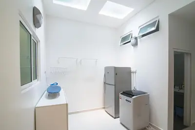 a white kitchen with a refrigerator and a sink at Landed Cozy House Near SPICE, Airport in Kampong Manggis