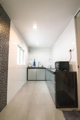 a kitchen with white walls and a counter with a microwave at Landed Cozy House Near SPICE, Airport in Kampong Manggis
