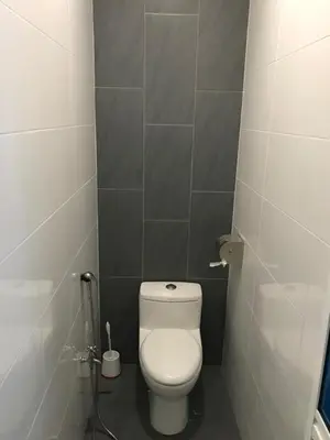 a bathroom with a white toilet in a stall at Landed Cozy House Near SPICE, Airport in Kampong Manggis
