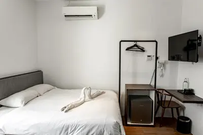 a bedroom with a bed and a desk and a tv at Earnest Hotel Georgetown in George Town