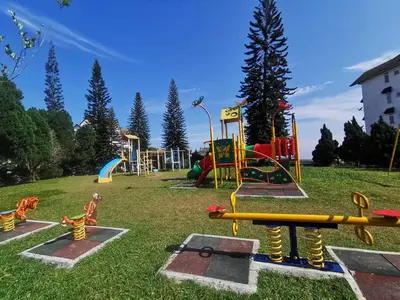 a playground with colorful equipment in a grass field at Little England B5-2 Fraser Panorama in Bukit Fraser