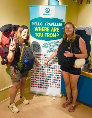 three women standing in front of a sign with backpacks at A3A Oastel CoLiving in Tanah Rata