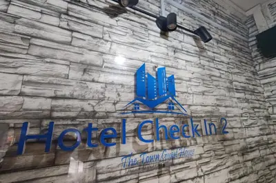 a sign on the side of a brick wall with a hotel check in at Hotel Check Inn 2 Cameron Highlands in Brinchang