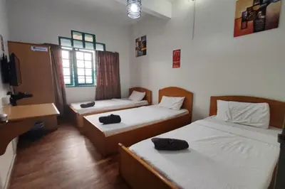 a room with two beds and a desk and a television at Hotel Check Inn 2 Cameron Highlands in Brinchang