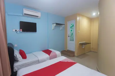 a hotel room with two beds and a tv at Hotel O Rafik Ali Motel in Kepala Batas