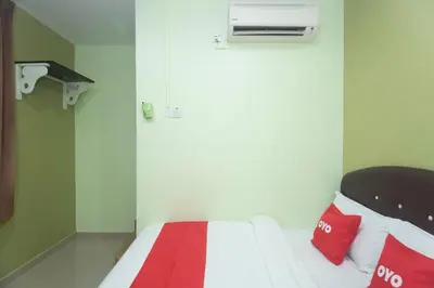 a small room with a bed with red and white pillows at Hotel O Rafik Ali Motel in Kepala Batas
