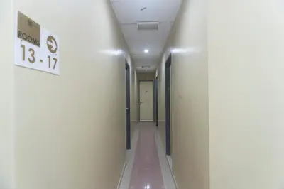 a hallway with white walls and a sign on a wall at Hotel O Rafik Ali Motel in Kepala Batas