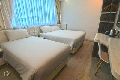 a hotel room with two beds and a table and a desk at Legacy Hotel Ipoh in Ipoh
