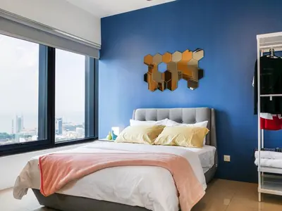 a bedroom with a blue wall and a bed at Tropicana 218 Macalister Studio with Seaview in George Town