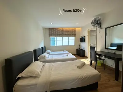 two beds in a room with a desk and a computer at Dear Dino House in Tanah Rata