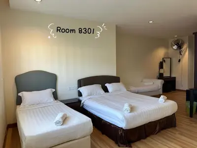 a room with two beds and a sign on the wall at Dear Dino House in Tanah Rata