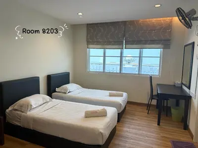 two beds in a room with a desk and a table at Dear Dino House in Tanah Rata