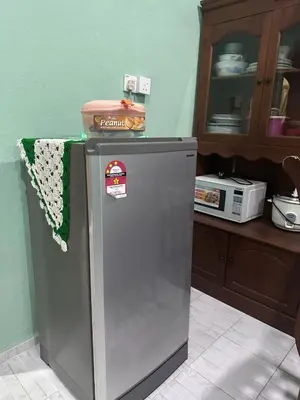 a refrigerator in a kitchen next to a microwave at AMIMAS HOMESTAY in Kampong Telok