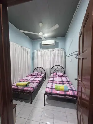 two twin beds in a room with a window at AMIMAS HOMESTAY in Kampong Telok