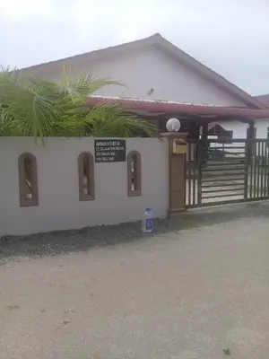a small white building with a sign on it at AMIMAS HOMESTAY in Kampong Telok