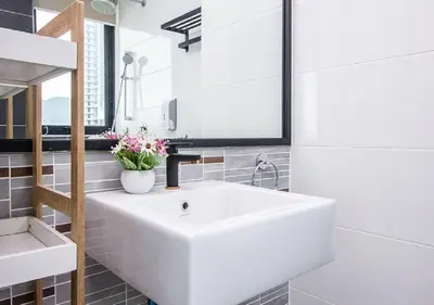 a white bathroom with a white sink and a mirror at Rumahku Gurney with 270 degree Sea View in George Town
