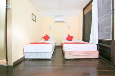 two beds in a small room with red pillows at Hotel O Ombak Inn Chalet in Pangkor