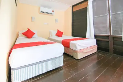 two beds in a small room with a window at Hotel O Ombak Inn Chalet in Pangkor