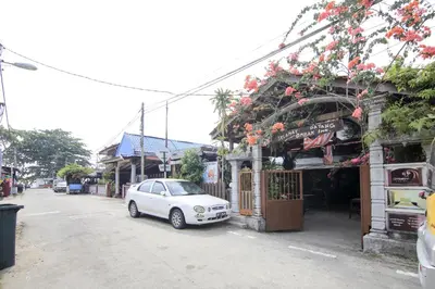 a white car parked in front of a building with flowers at Hotel O Ombak Inn Chalet in Pangkor