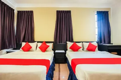 a hotel room with two beds with red pillows at Hotel Home 88 in Teluk Intan