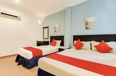 two beds in a hotel room with red pillows at Hotel Home 88 in Teluk Intan