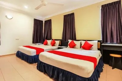 a hotel room with two beds with red pillows at Hotel Home 88 in Teluk Intan