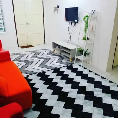 a living room with a red couch and a black and white rug at Nur Zahra Sungkai Homestay in Sungkai