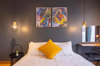 a bed with a yellow pillow and three paintings on the wall at Georgetown Tropicana 218 by Airlevate Suites in George Town