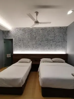 a bedroom with two beds and a ceiling fan at Lumut Hotel in Lumut