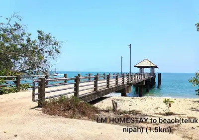 a wooden pier on a beach with the ocean at EM HOMESTAY(Coral Bay 3Room Apartment) in Pangkor